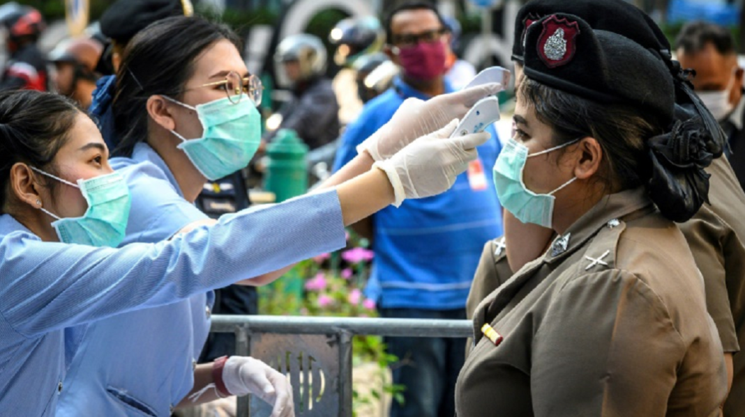 -Des agents de santé publique vérifient la température d'officiers de police, le 1er mars 2020 à Bangkok